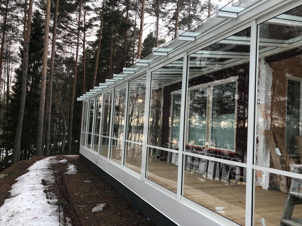 Pitkä lasitettu terassi metsän reunassa